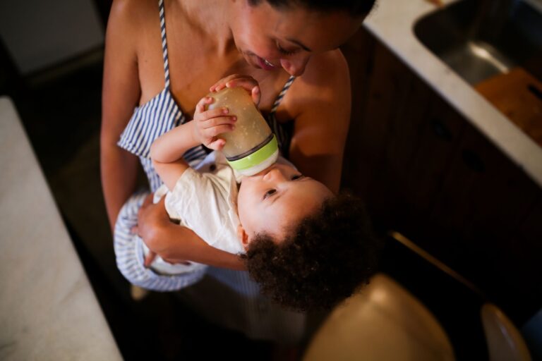 Mãe alimentando bebê com mamadeira em casa